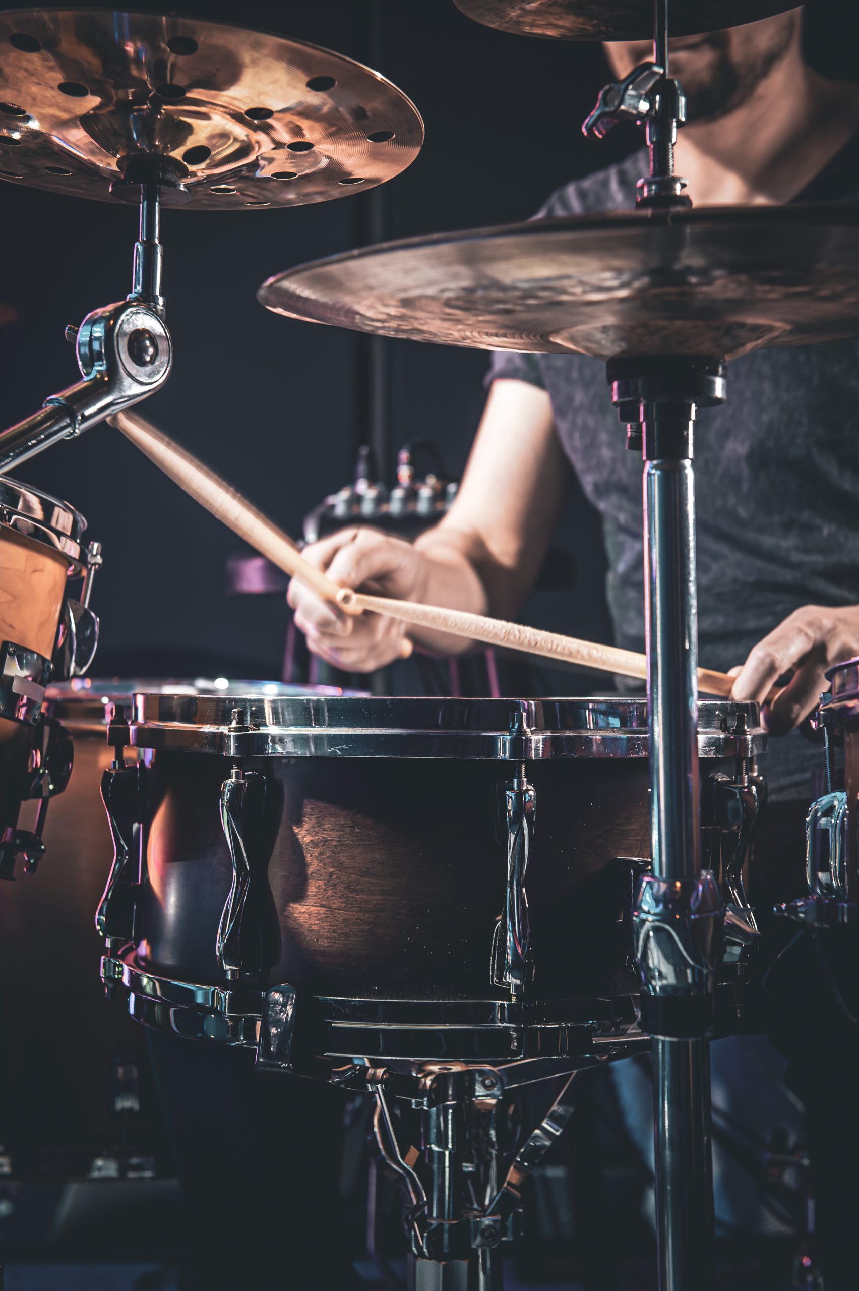 Male drummer plays drums in a dark room, percussion instrument.